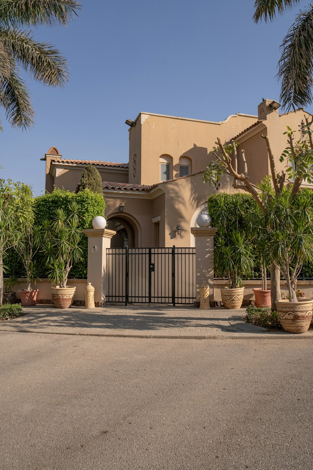 large tan house with gated entrance and lush greenery rx i1kjmkw8